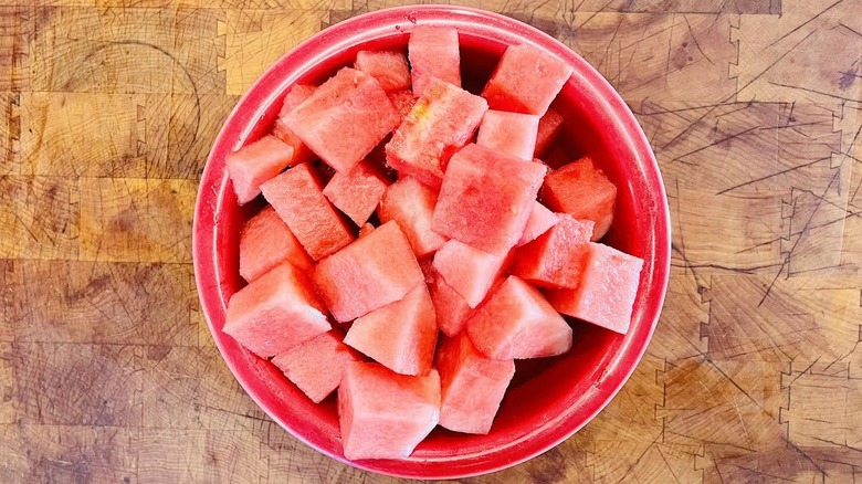 Large red bowl full of cubed watermelon