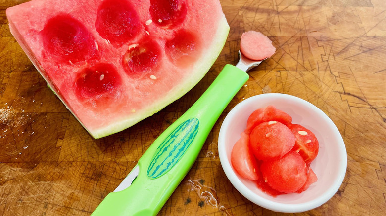 Chunk of watermelon with melon baller and dish of melon balls