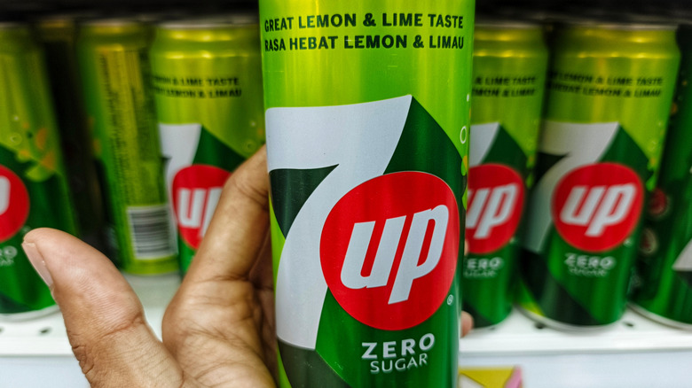 Close-up of a hand holding a 7UP Zero Sugar can in a supermarket,