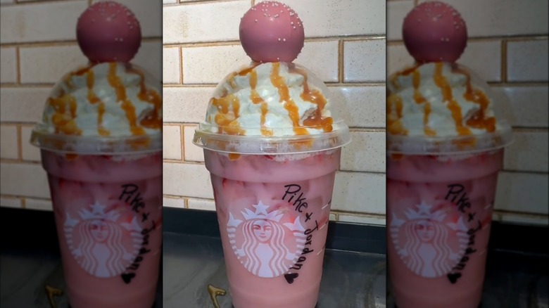 A Starbucks pink drink is topped with whipped cream, caramel, and a birthday cake cakepop