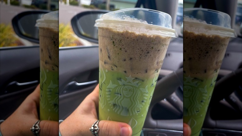 Hand holding up a large Starbucks "Dubai chocolate" drink in car