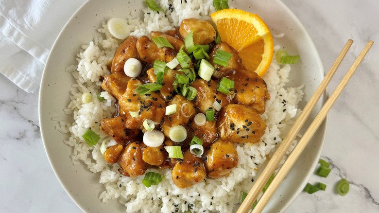 orange chicken with rice and scallions in bowl