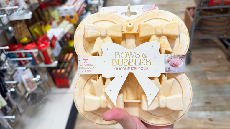 A hand holds up a silicone mold in the shape of bows