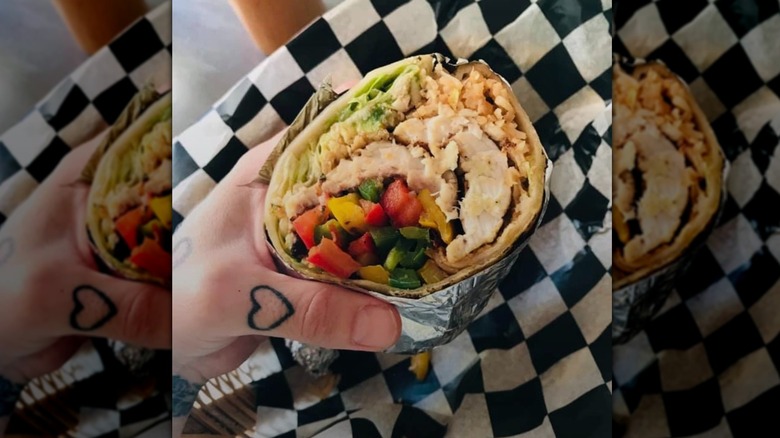Hand holding hearty burrito from Burrito Revolution