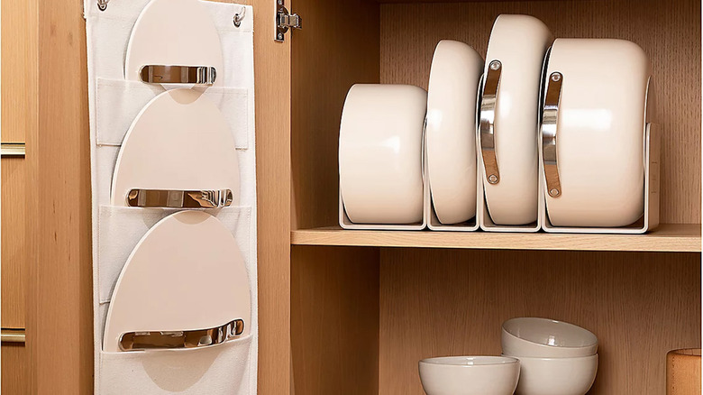 Caraway Home pots, pans, and lids sit nestled in a cupboard