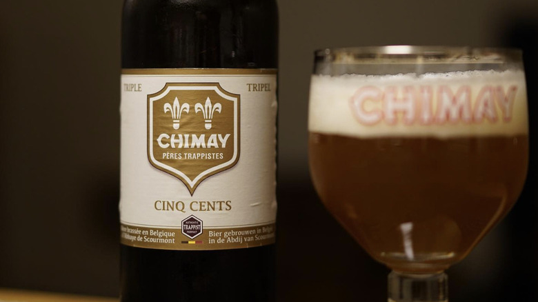 Bottle of Chimay Cinq Cents tripel beer next to a Chimay glass