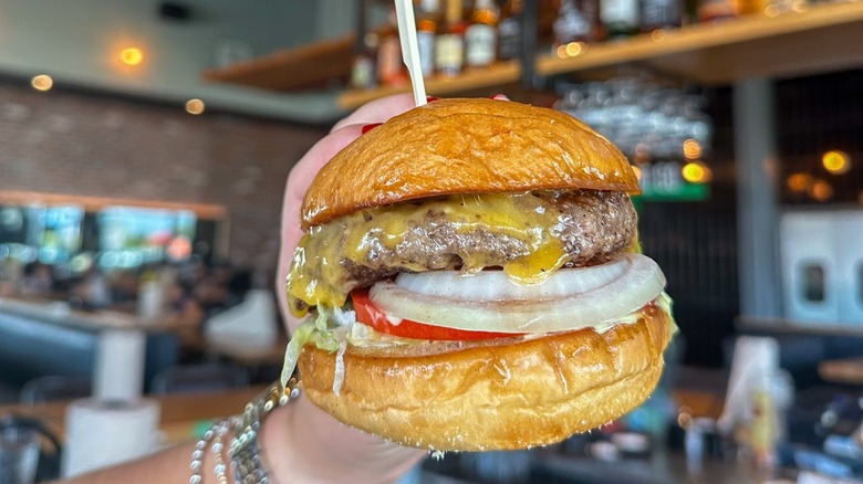 a close up of a hopdoddy burger dripping with cheese