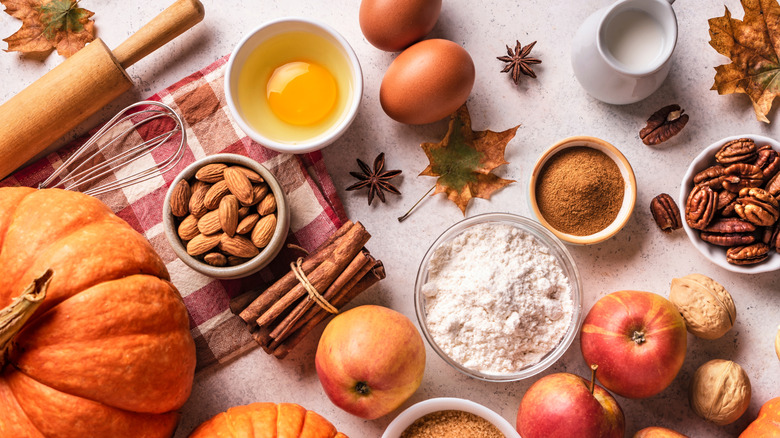 Autumn fall baking background with pumpkins, apples, nuts, food ingredients and seasonal spices