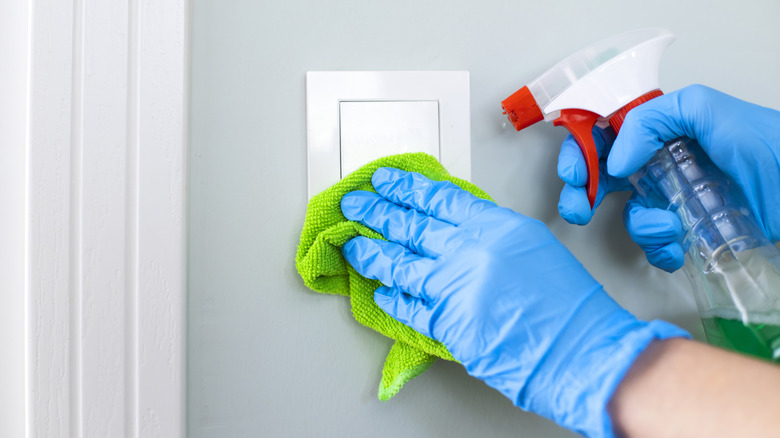 Cleaning a light switch with disinfectant spray