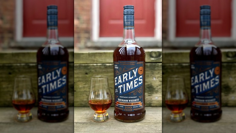 A bottle of Early Times Bottled in Bond with a glass of whiskey beside it