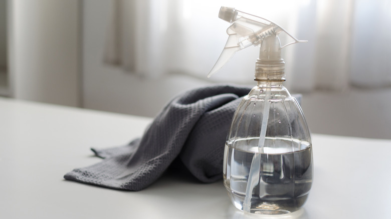 Spray bottle filled with pure water and vinegar with a cloth next to it