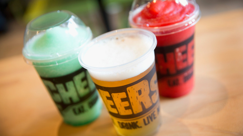 Taco Bell Cantina alcoholic beverage options, including a Baja Blast Freeze, Strawberry Freeze, and glass of amber-colored beer