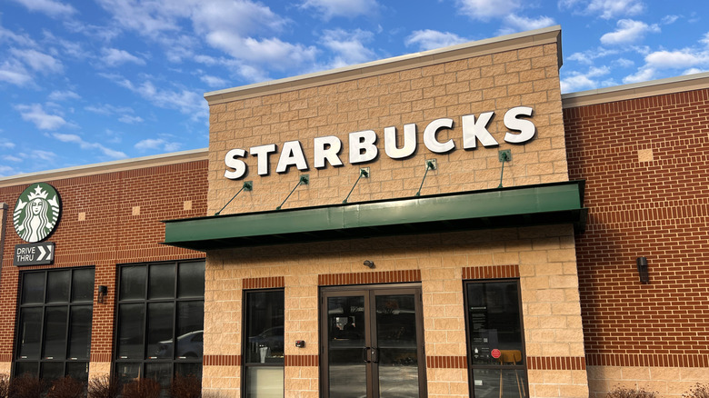 Starbucks Frappuccino on a brown countertop in the hands of a person wearing a pink sweatshirt