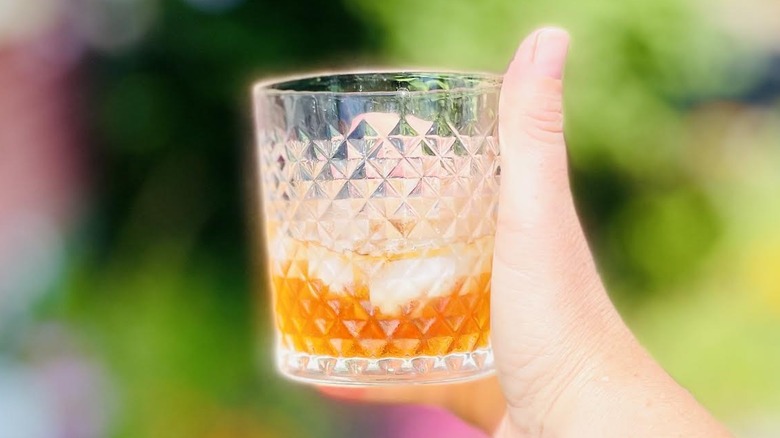 Hand holding glass of Jack Daniel's Tennessee Blackberry Whiskey on the rocks