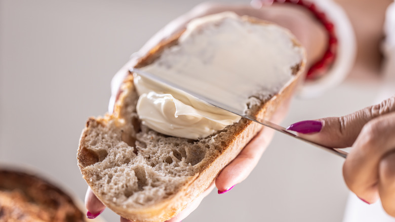Hand spreading butter on slice of bread