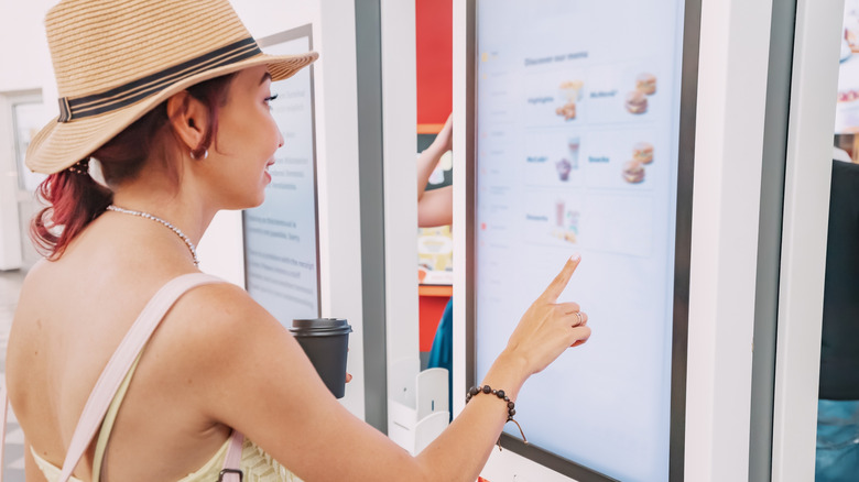A person orders from an automated menu kiosk at a fast food restaurant