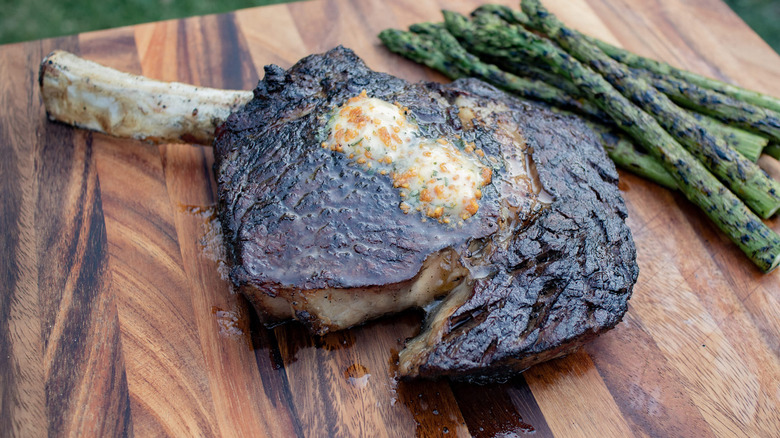 Pittsburgh Rare steak on a wooden cutting board with grilled asparagus nearby