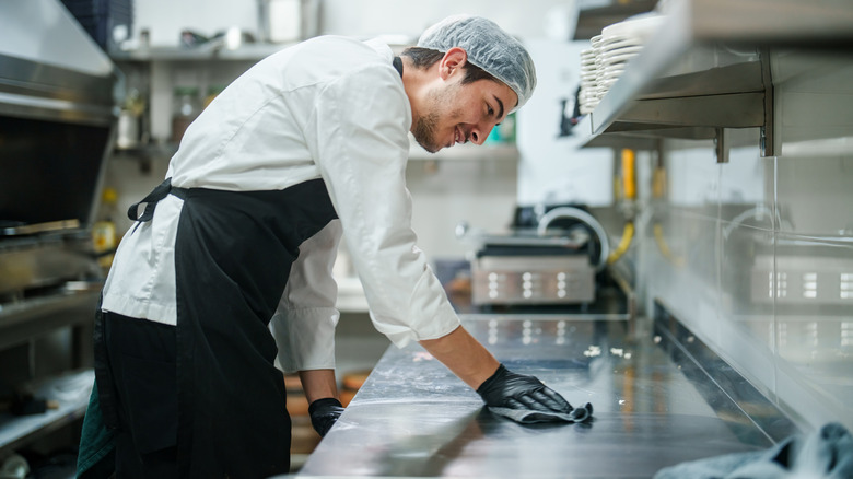 Chef cleaning a stainless steel countertop