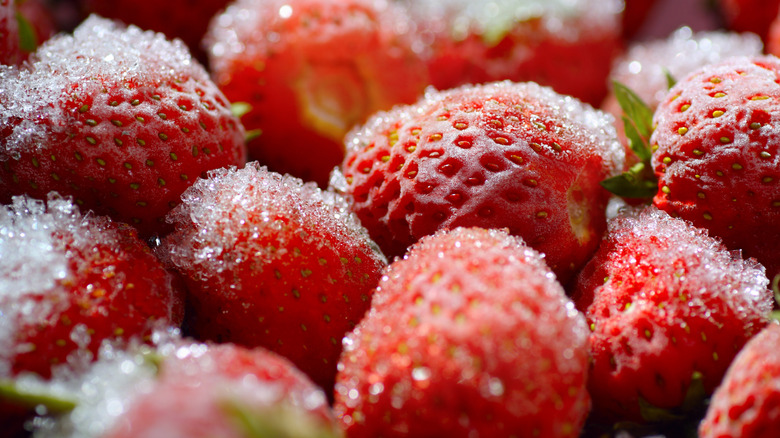 Frozen strawberries sit in a pile, seen in close-up