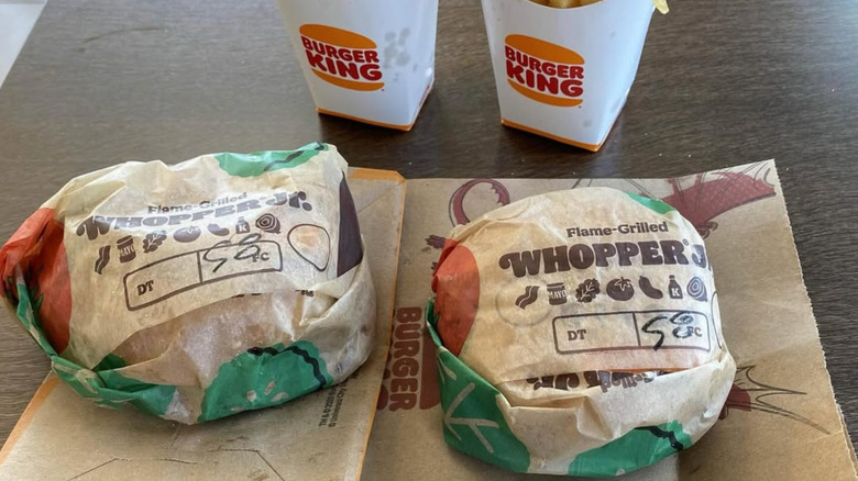 Two wrapped Whoppers sit on a Burger King table
