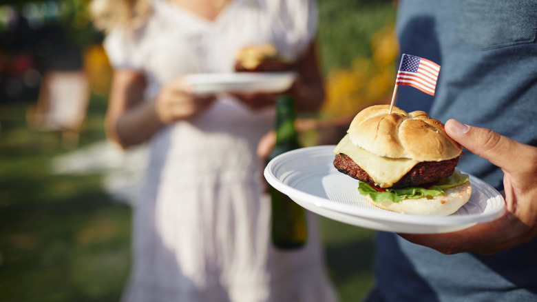 Man holding a burger with a small American flag