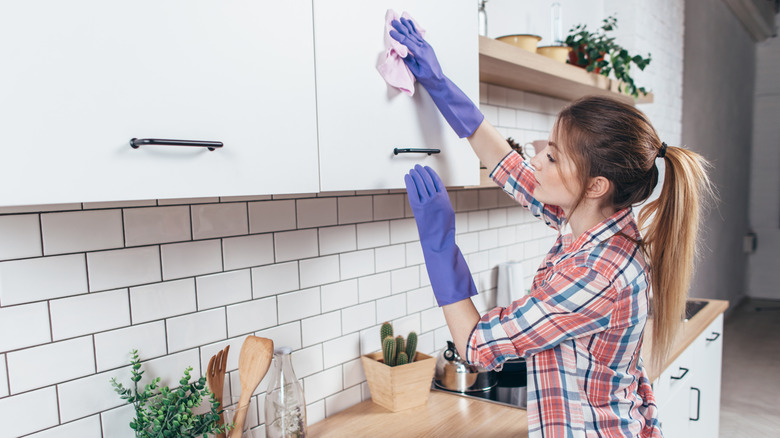 Young woman washing a kitchen cabinet