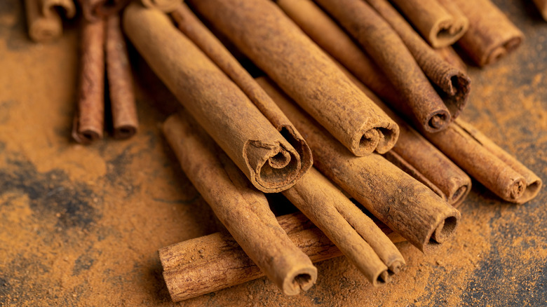 A collection of whole cinnamon sticks on cinnamon powder