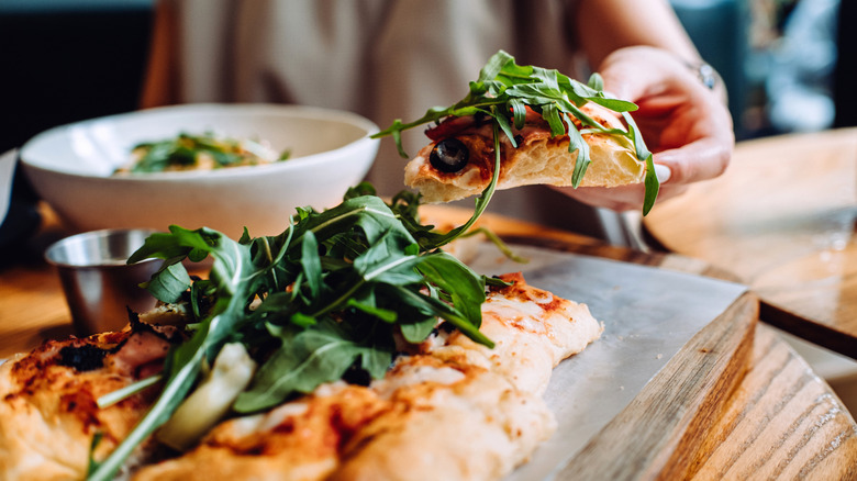 person enjoyed pizza topped with arugula