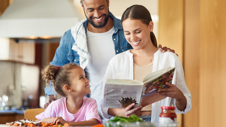 family using cookbook to make food