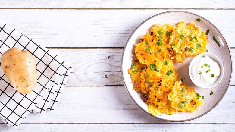 Latkes on white plate with sour cream and minced green onions