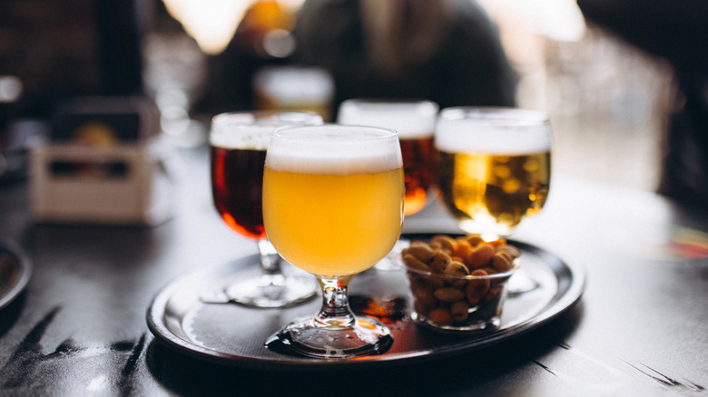 Four glasses on a tray with peanuts