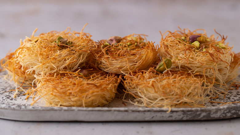 Kataifi nests topped with pistachio on a serving platter