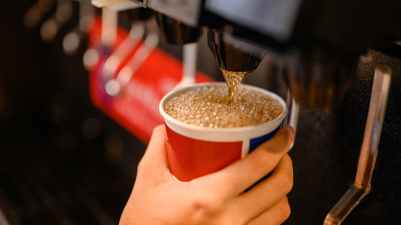 A close up on a customer filling a cup full of soda at a beverage dispenser
