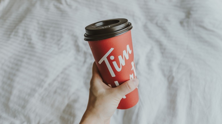 holding Tim Hortons' to-go cup of coffee
