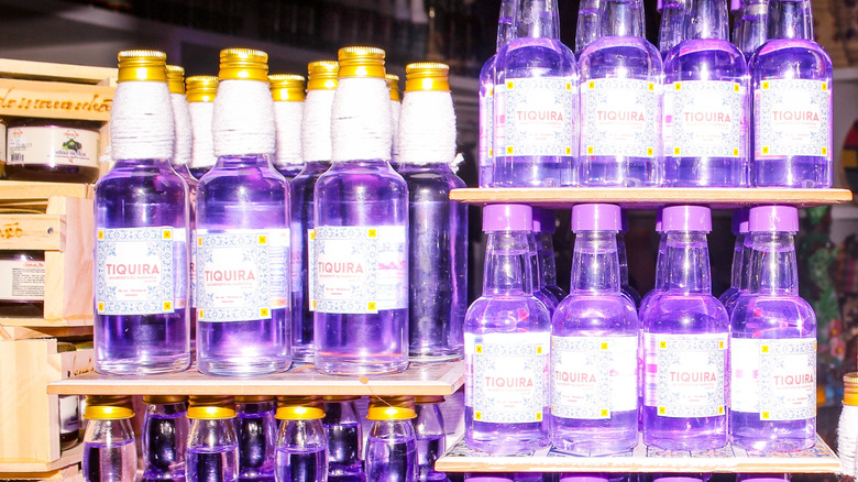Bottles of purple liquor called tiquira line a bar.