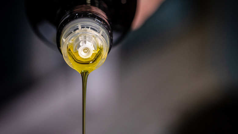 A person pours out olive oil from the bottle