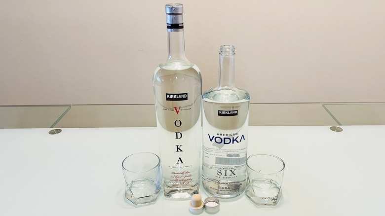 Opened bottles of Kirkland Signature French and American Vodkas with glasses alongside