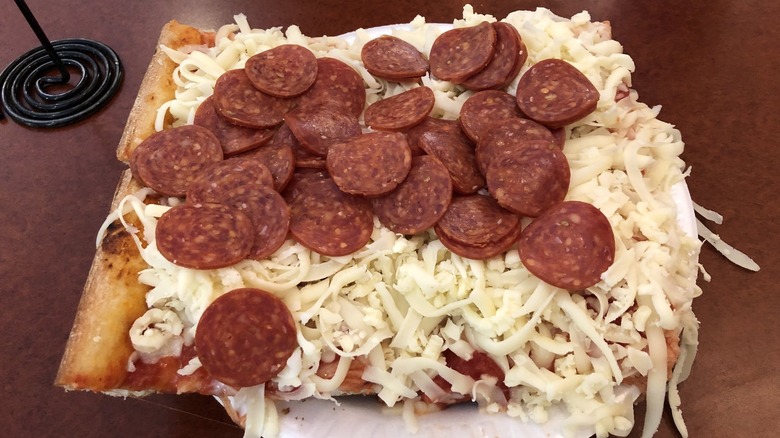 Slice of Beto's pizza topped with cold cheese and pepperoni