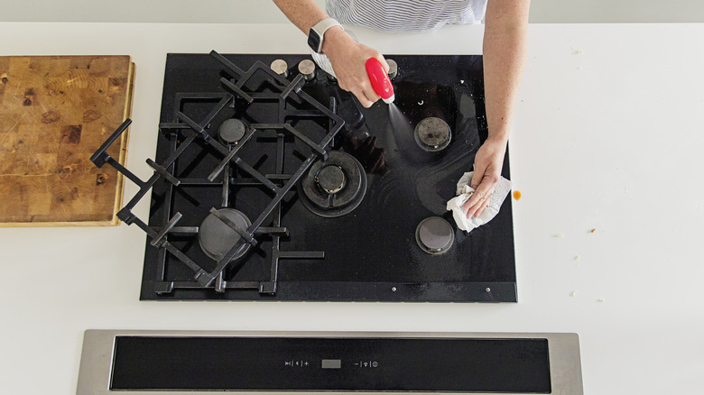 Person cleaning stove with all purpose cleaner