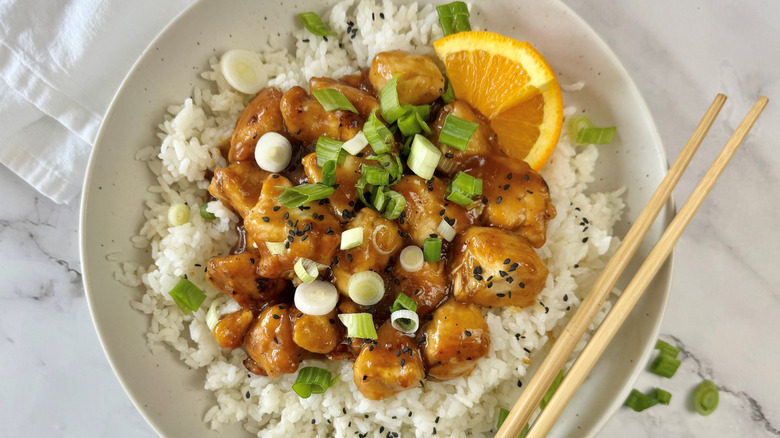 orange chicken with rice in bowl with chopsticks