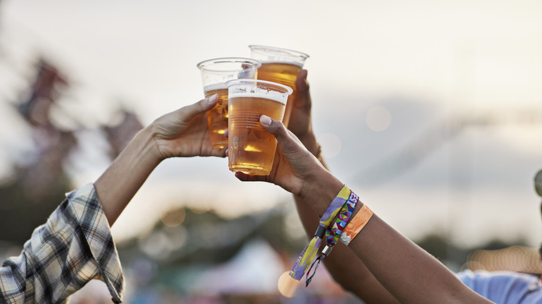 Three friends raise their cups of beer to cheers each other