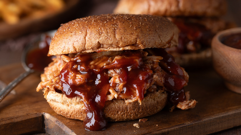 A pulled pork sandwich has rich barbecue sauce running down its side