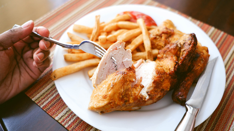 Diner eating roasted chicken and french fries
