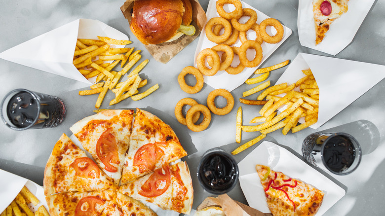 A selection of burgers and pizza on a grey table