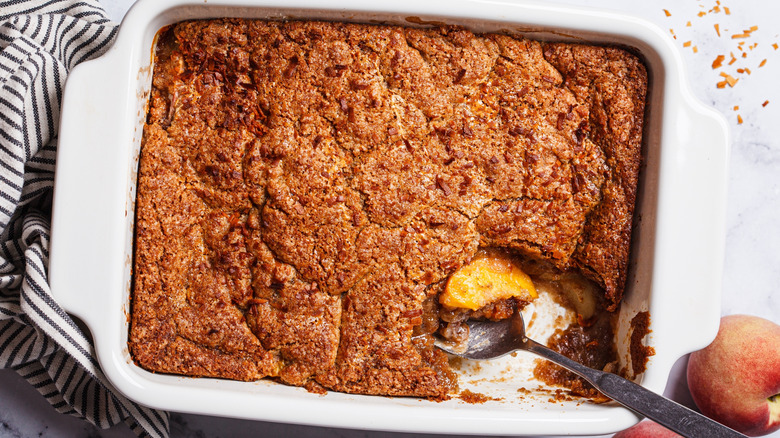 A spoon sits in a pan of freshly baked cobbler