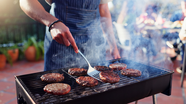 Person grilling burgers on a small outdoors grill