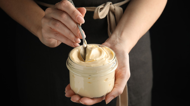 Baker holding open jar of mayo with a spoon