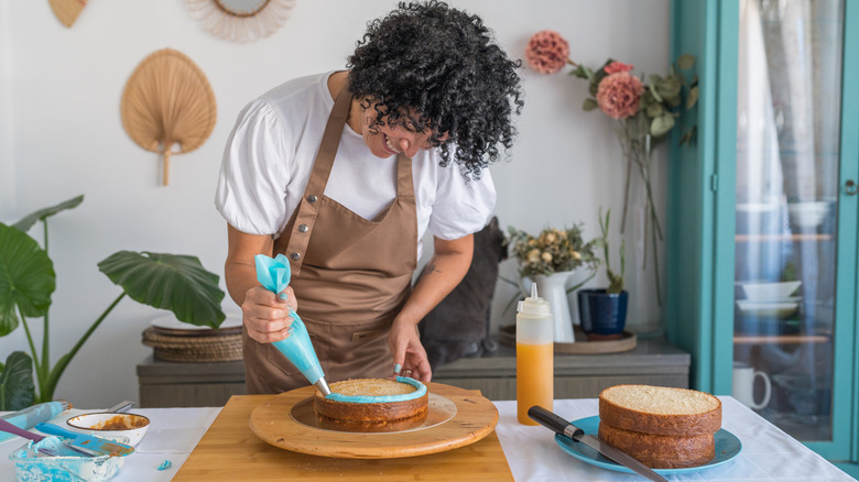 A person icing a cake with bright blue frosting.