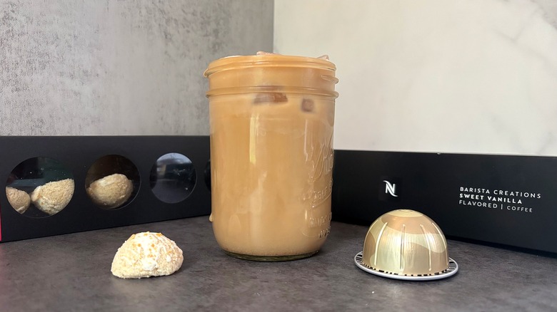 Nexpresso x Milk Bar box of bombs, pods, behind cup of iced coffee and singular bomb and pod on black surface