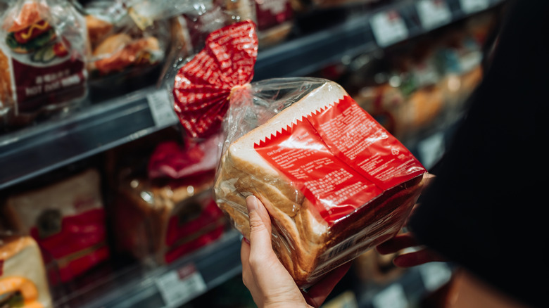 A shopper examines a loaf of bread at the bread aisle